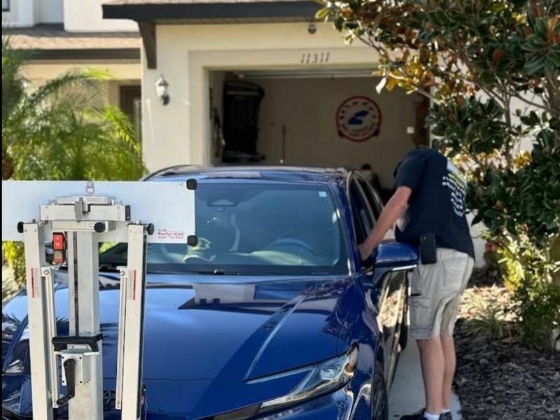 Windshield replacement in a customer's driveway, with the ADAS calibration rig set up right on site.