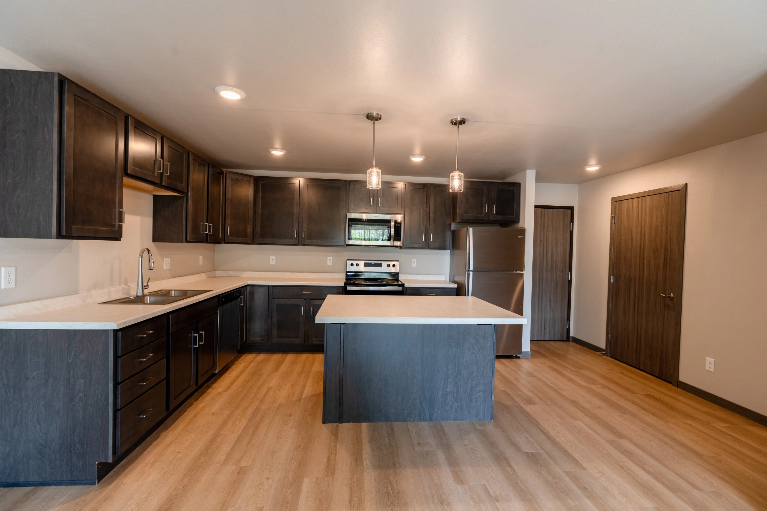 A kitchen with dark wood cabinets and a white counter top.