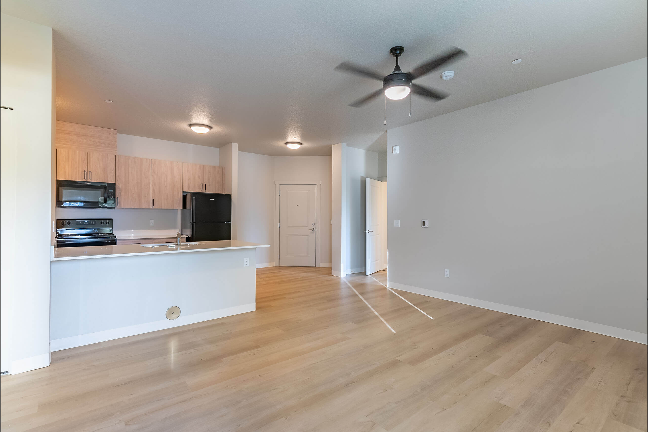 A room with a ceiling fan and wooden floors.