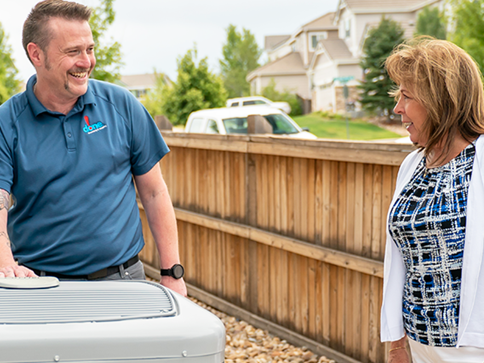 A Done HVAC Technician talking to a customer outside by the AC unit