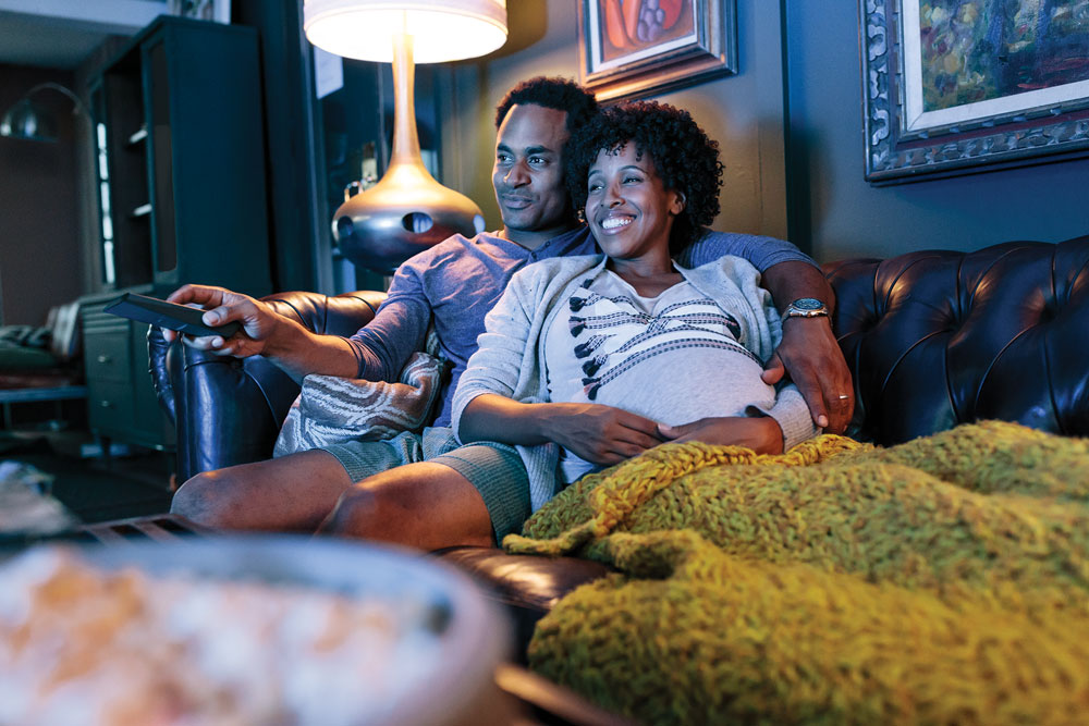 Pregnant couple watching TV together image