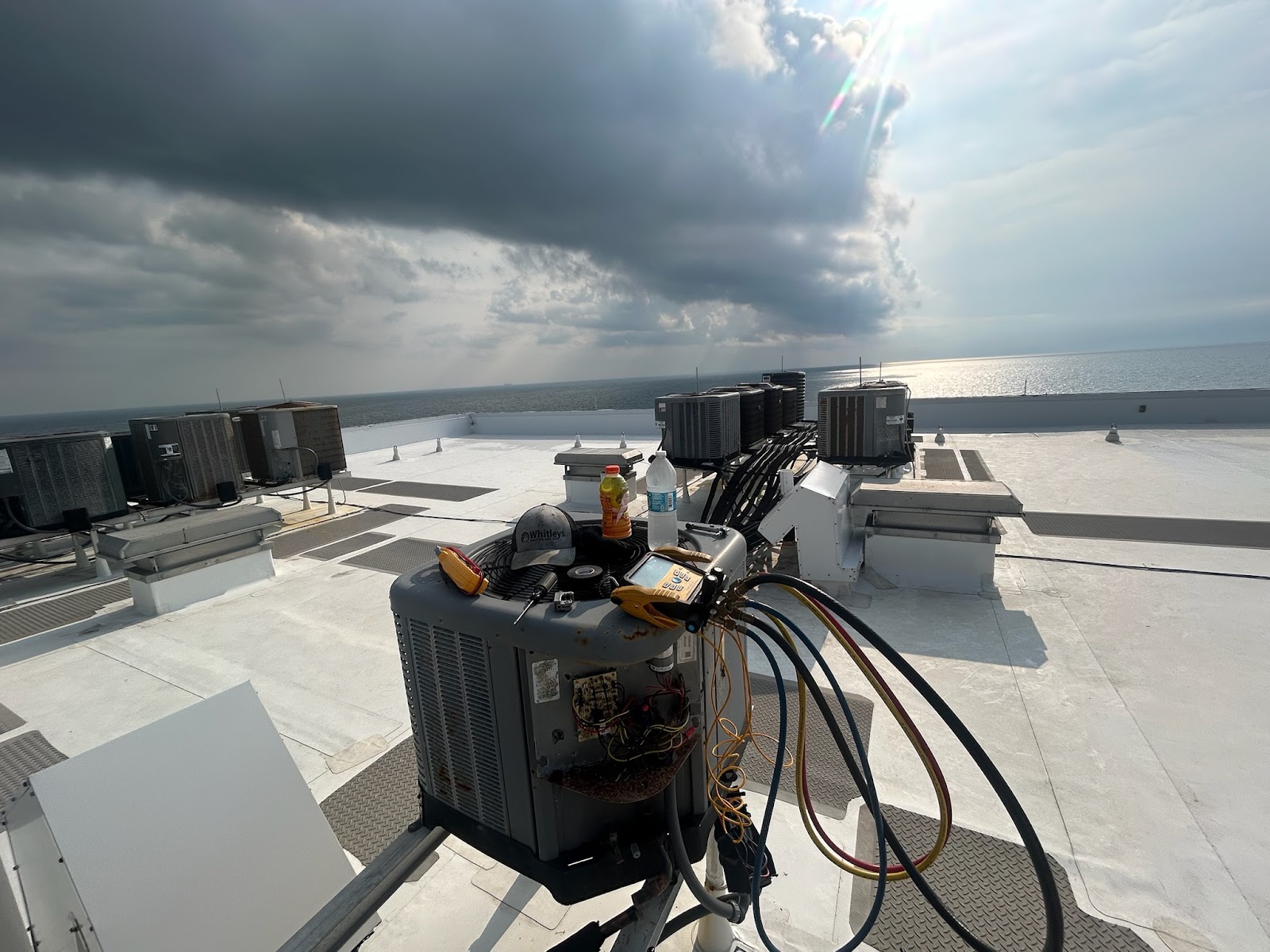 A rooftop scene with multiple air conditioning units and HVAC equipment. In the foreground, a large  