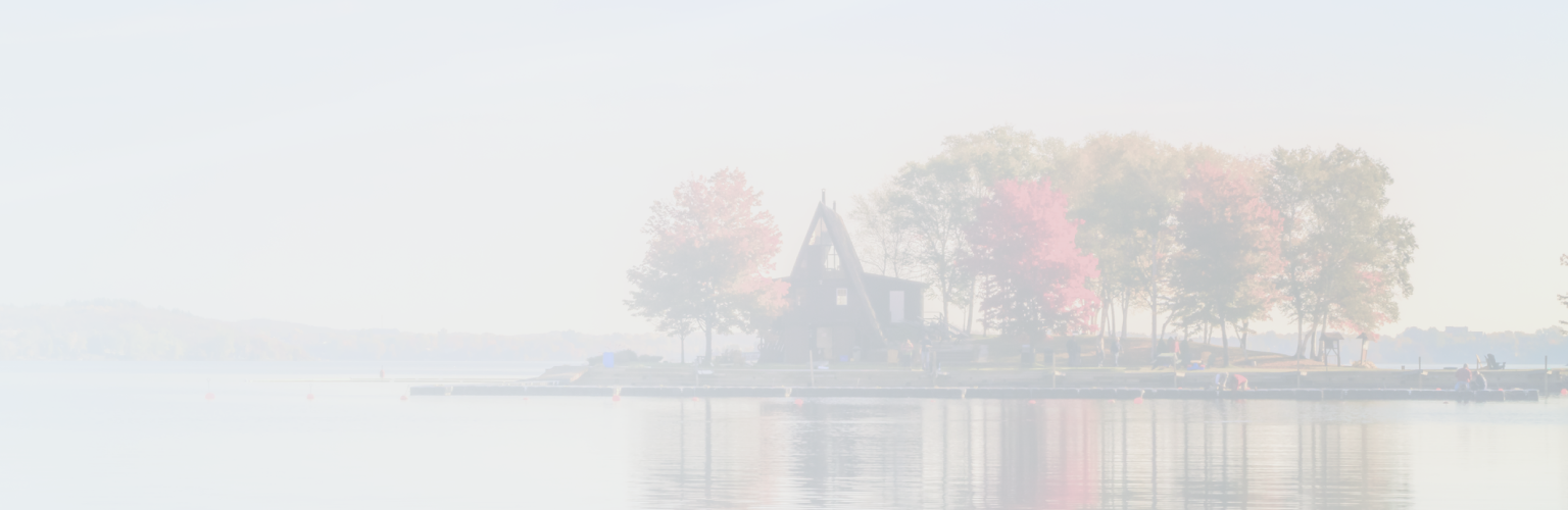 An A-frame lakeside cottage surrounded by colourful autumn trees.