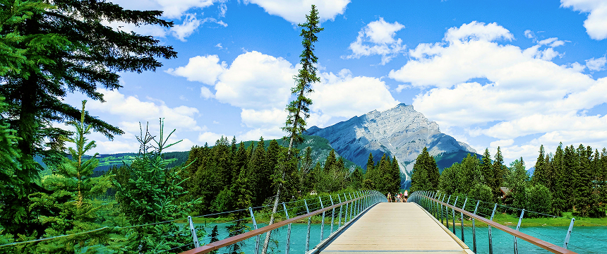 A bridge over a park that leads to a mountain.