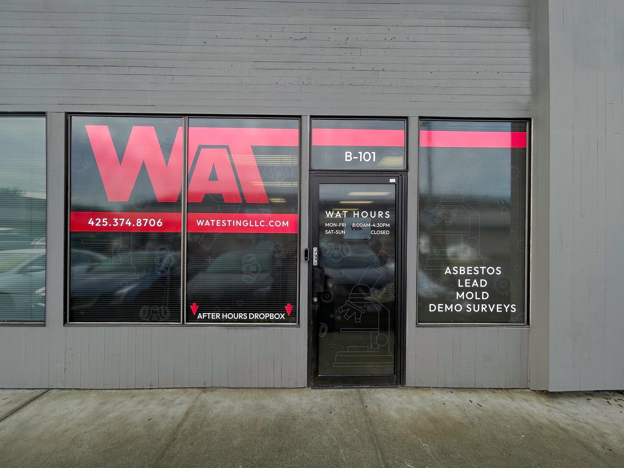 Perforated window film and door graphics for WAT's storefront, branding the glass while keeping the view out.