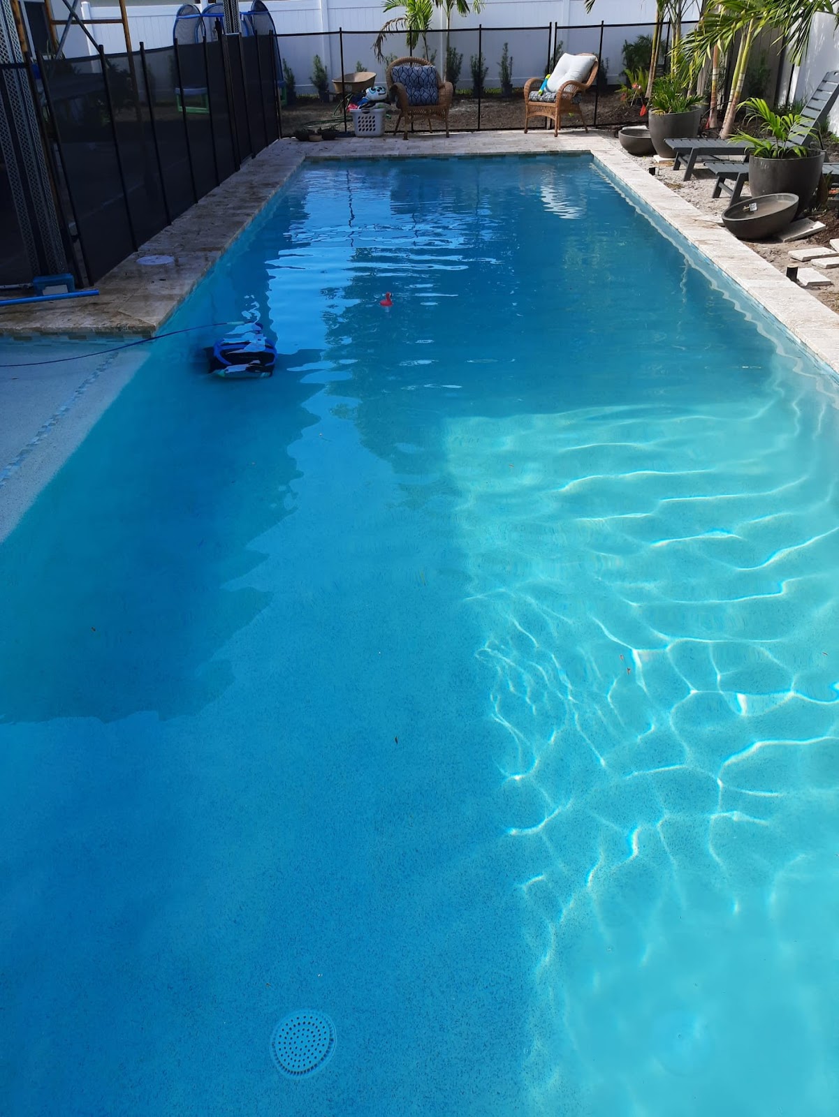 Large rectangular backyard swimming pool with bright blue water, surrounding patio space, and a private residential setting.