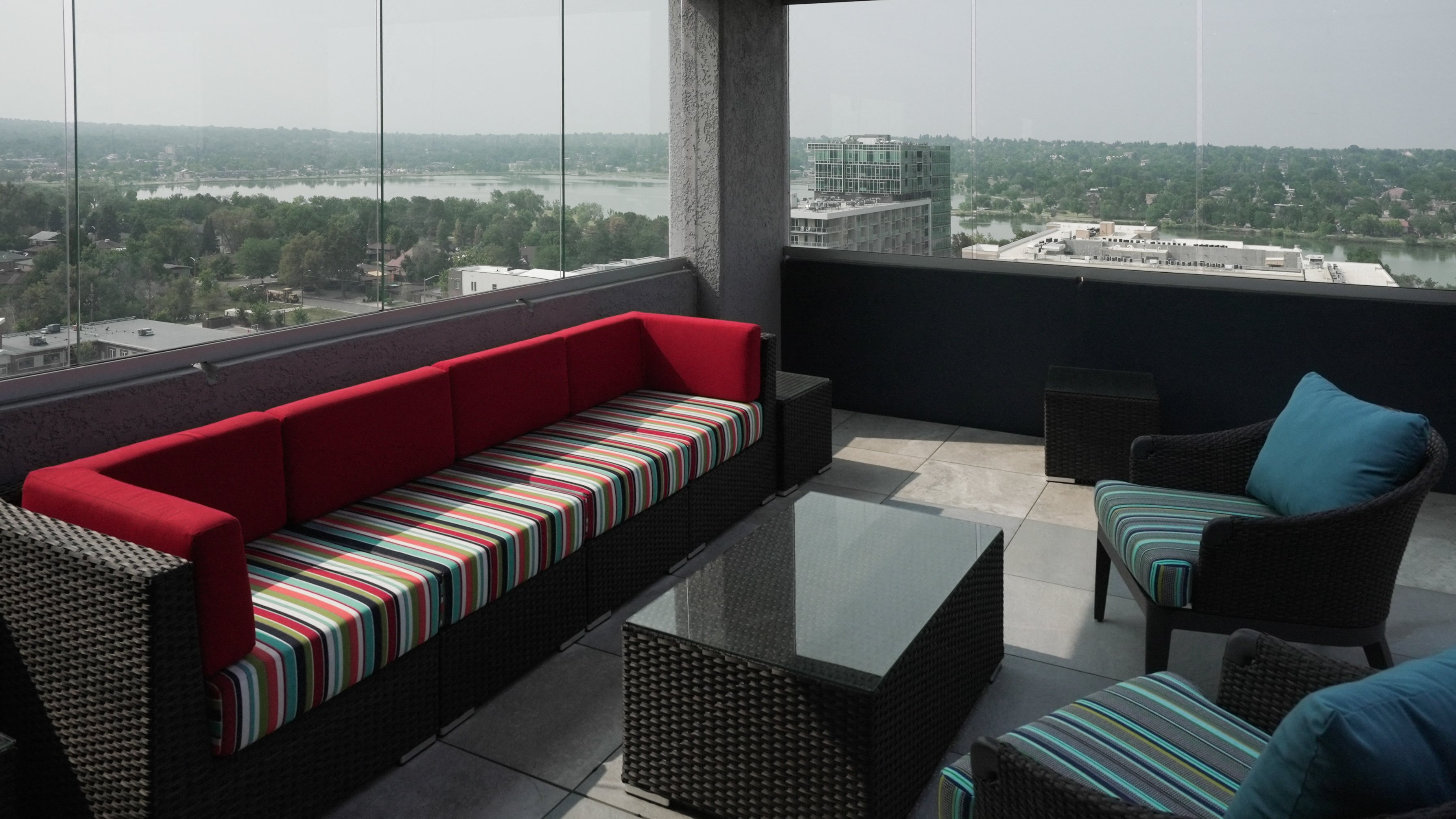 A red couch with a striped pattern sits in a room with a view of the city.