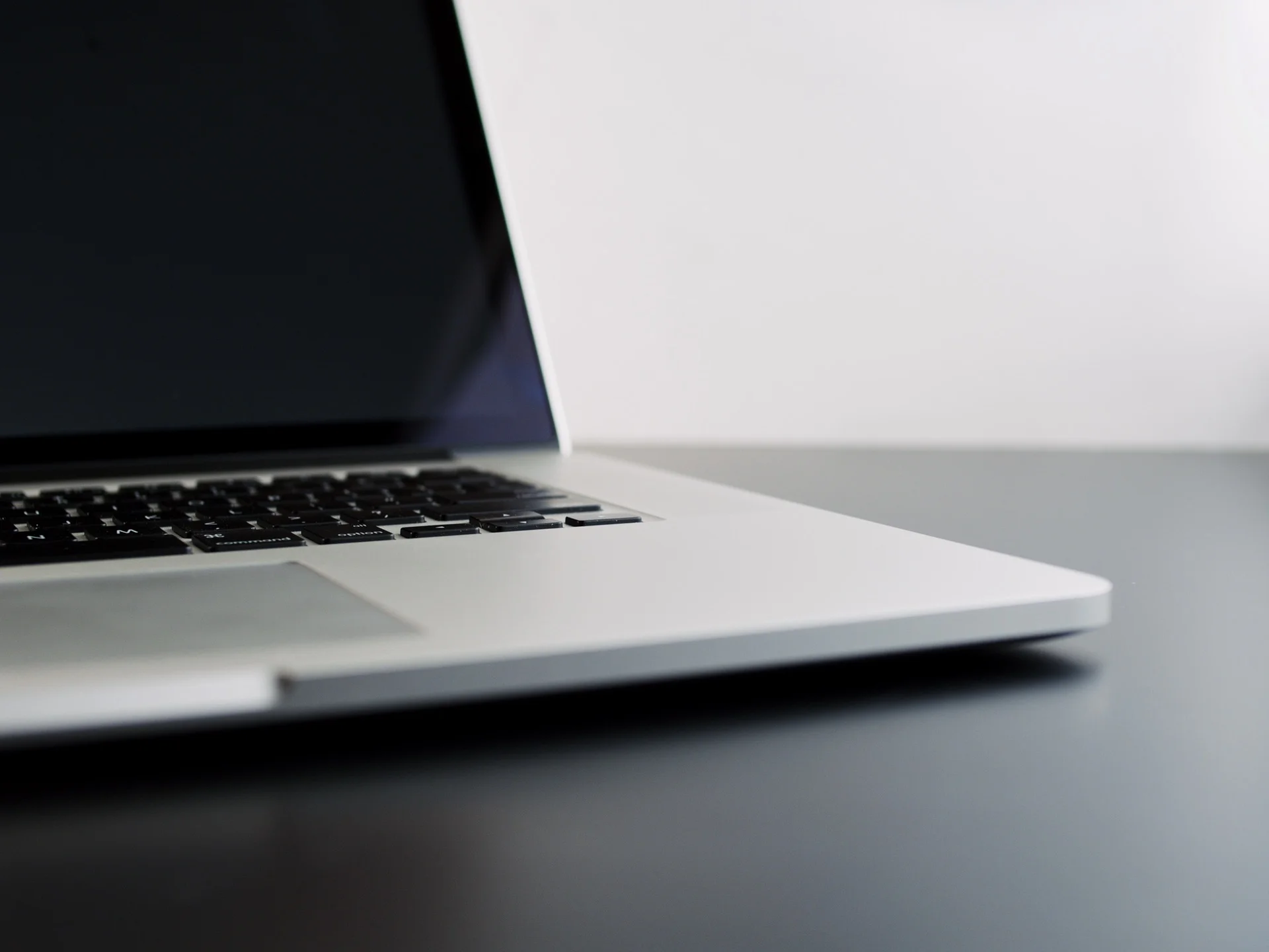 A close-up, low-angle shot of an open laptop computer on a dark surface, with a white background.
