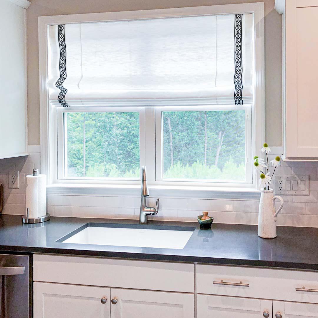Roman shades provide softness and customizable options to create a cozy and unique look in your home. We love how this customer matched their countertops with these custom-banded Roman shades.