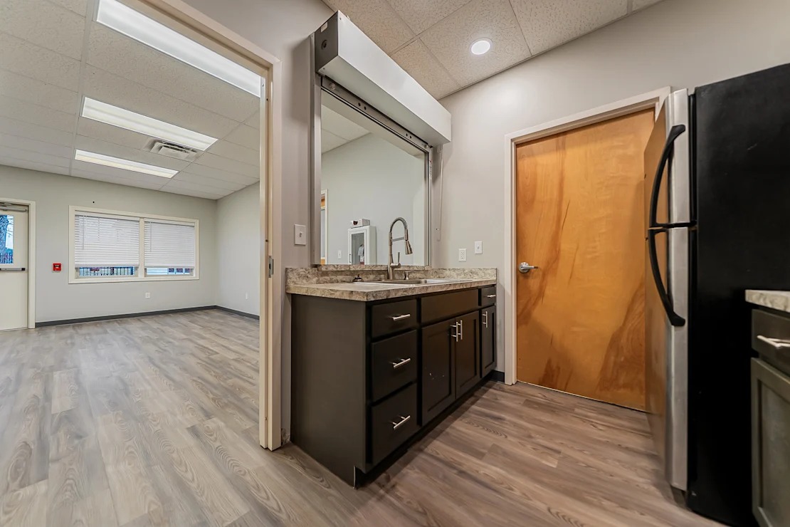 A kitchen with a wooden door and a black refrigerator.