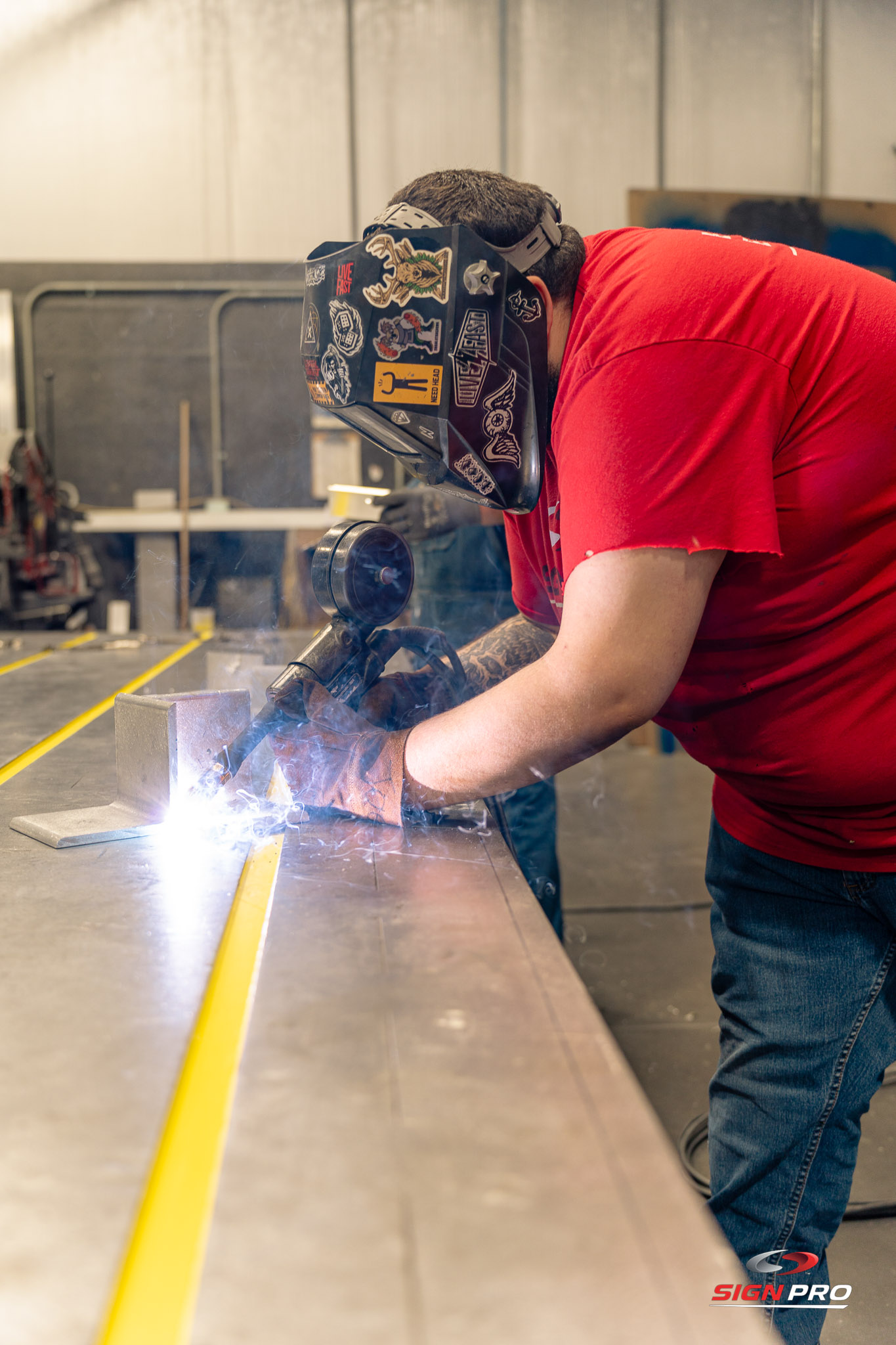 A skilled Sign Pro fabricator welding custom metal signage components inside the production facility, showcasing in-house craftsmanship and precision metalwork.
