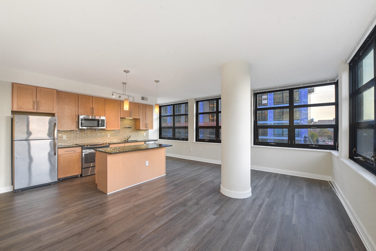 A kitchen with a refrigerator, microwave, and oven.