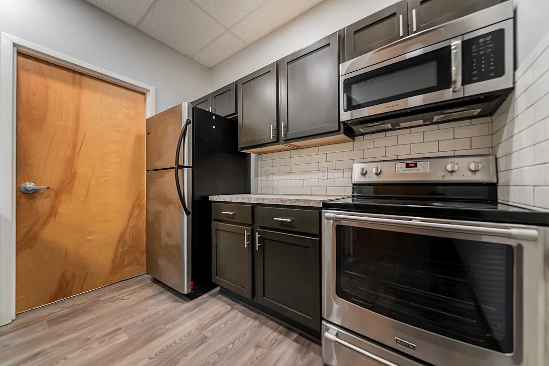 A kitchen with a refrigerator, oven, and microwave.