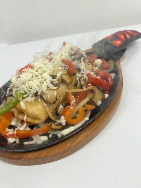 Crispy chimichanga served sizzling with grilled peppers, onions, mushrooms, tomatoes, and melted cheese at Catramex Restaurant.