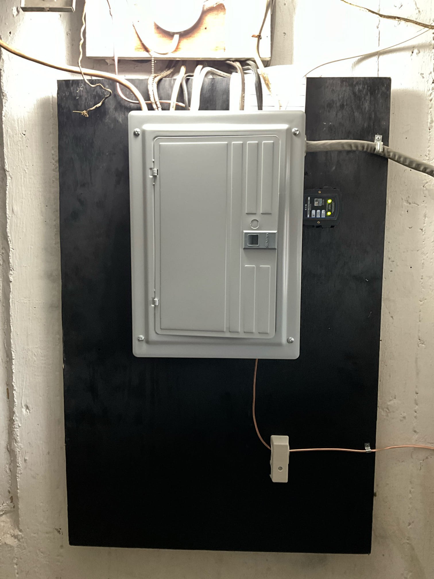 Thomas Edison Electric upgraded this breaker panel in a Drexel Hill, PA basement. The panel is cleanly mounted on a painted backer board with an Eaton surge protector alongside, and a phone line connection below for a tidy, organized utility area.