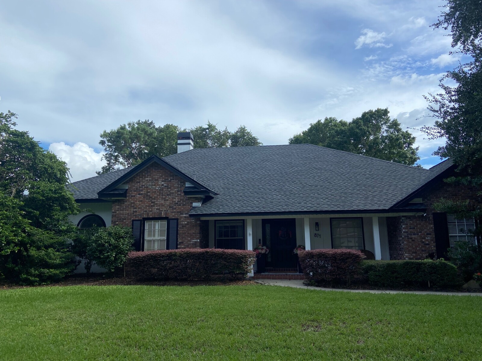 Wide front view of a completed dark asphalt shingle roofing system on a residential property.
