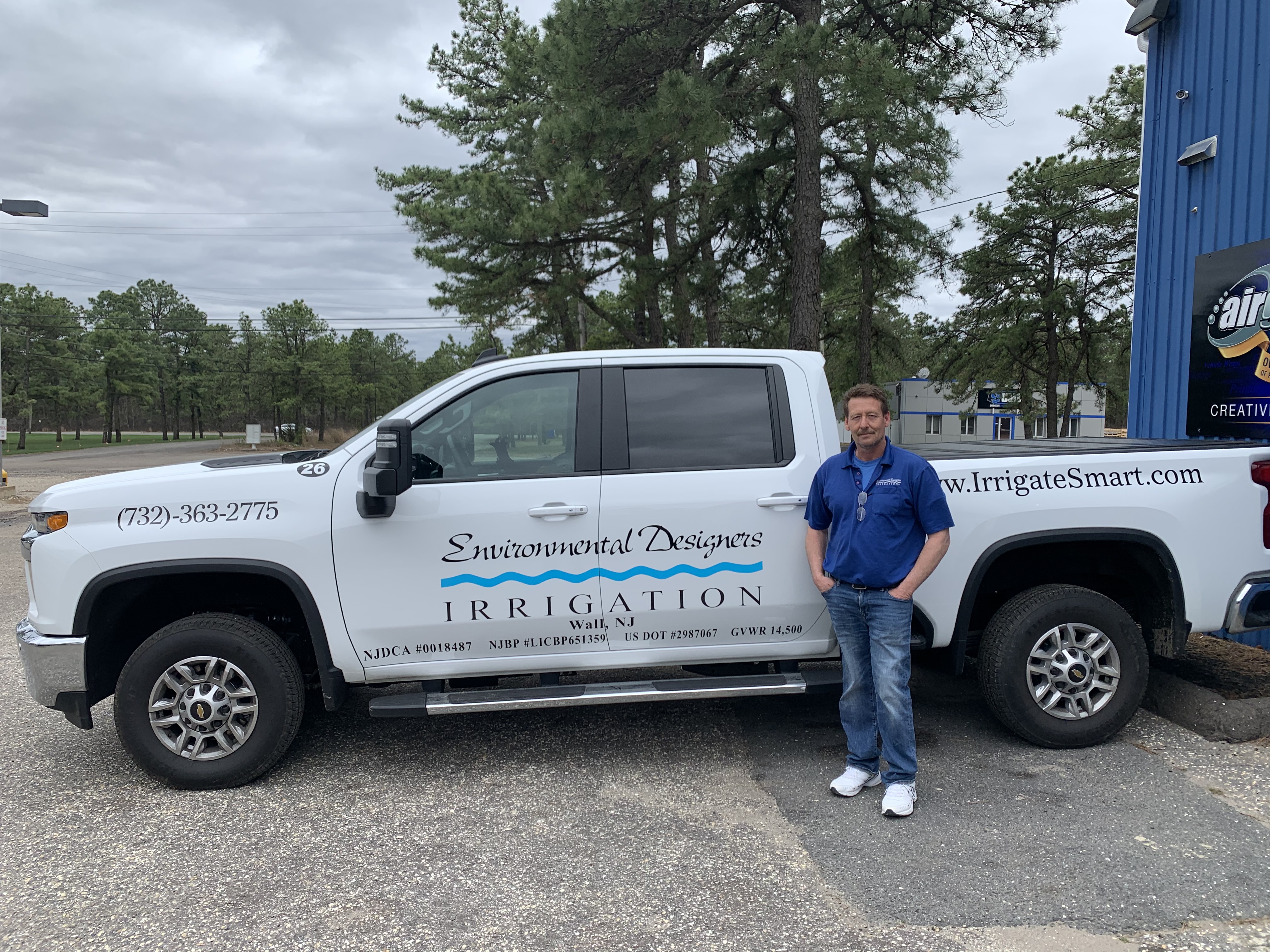 An Environmental Designers Irrigation company service pickup truck parked with a team member standing beside it.