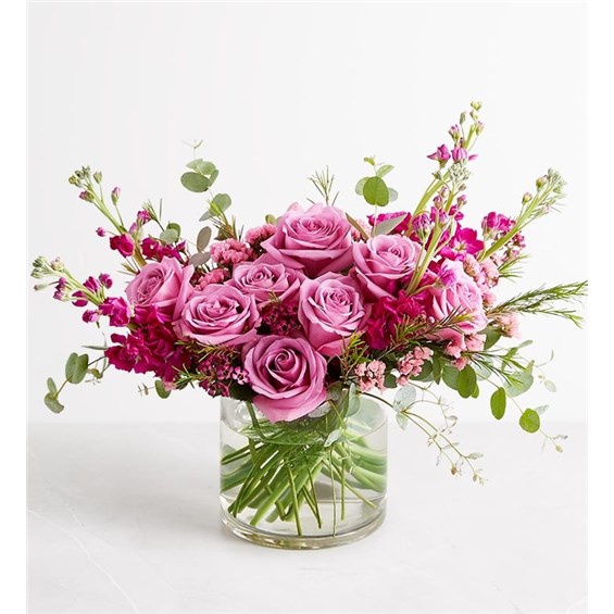 Roses and other classic blooms are artfully arranged in a fresh crescent-shape silhouette, resulting in a bouquet certain to delight traditionalists and trend-seekers alike. With its dreamy palette of lavenders and pinks, this arrangement will evoke the joys of spring regardless of the season.