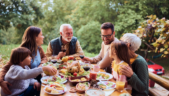 A multigenerational family gathered around an outdoor dinner table.