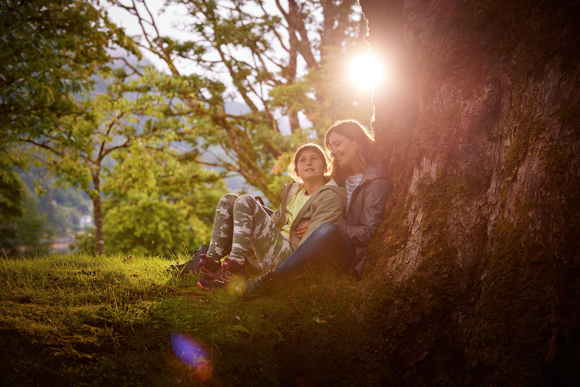 Mum and daughter sit under a tree on the grounds of Drimsynie Estate