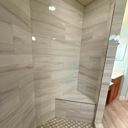 Completed bathroom renovation with a sliding glass shower door and tiled walls. 