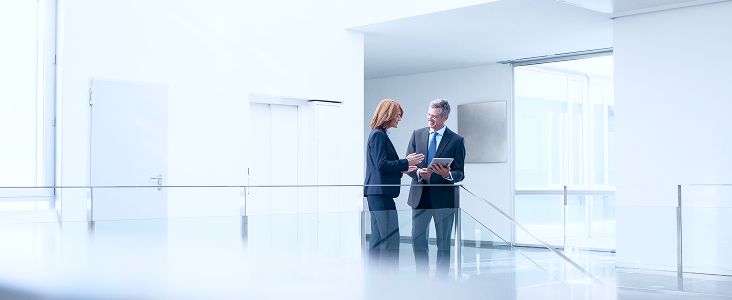 Two people standing in an office hallway.