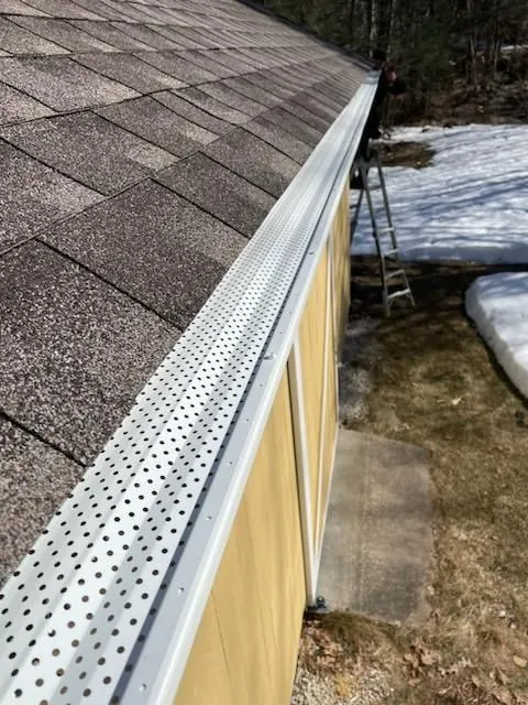 Perforated gutter protection system installed along roof edges. Designed to block debris while allow 
