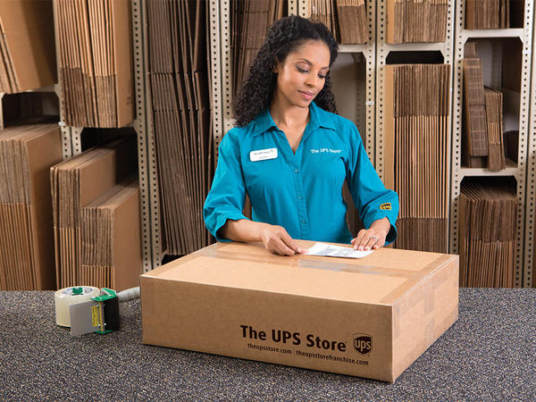 El auxiliar de The UPS Store pegando una etiqueta a una caja