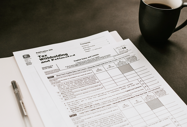 A series of financial documents next to a cup of coffee.