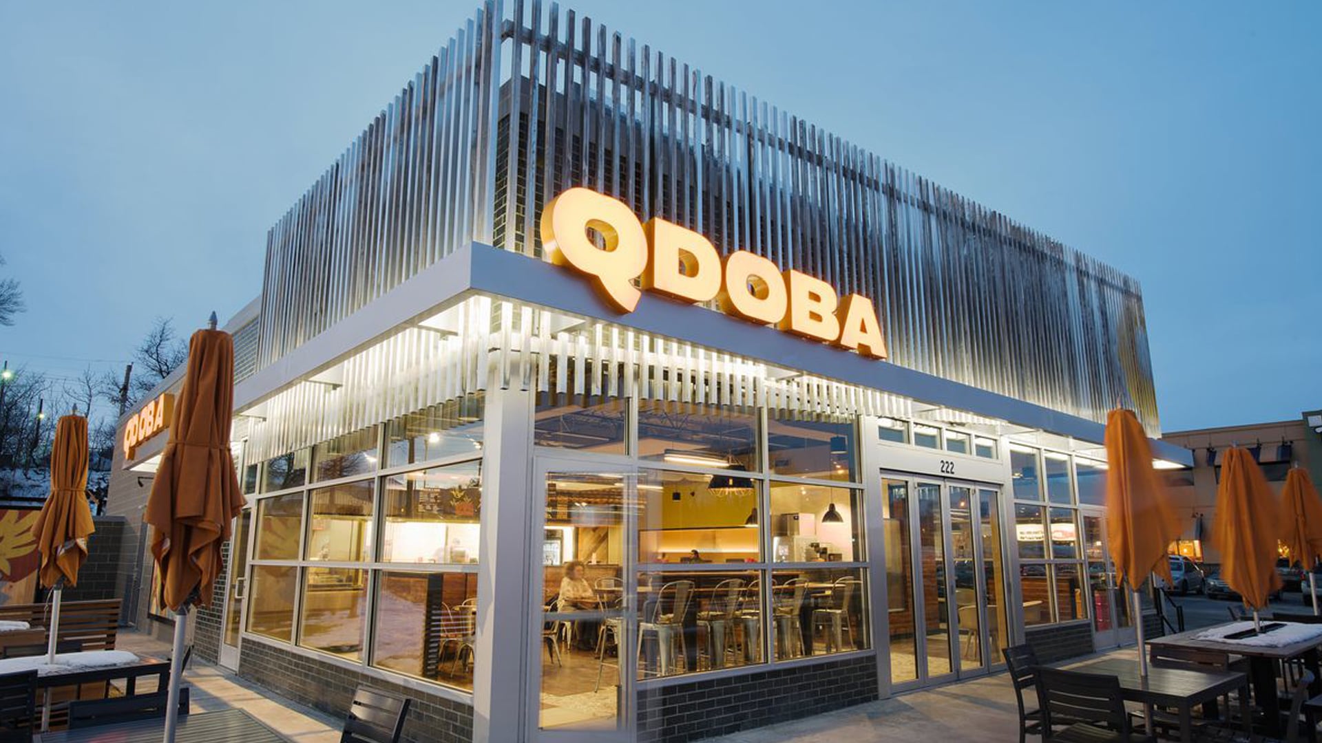 Une façade de magasin Qdoba avec un patio pour manger à l'extérieur.