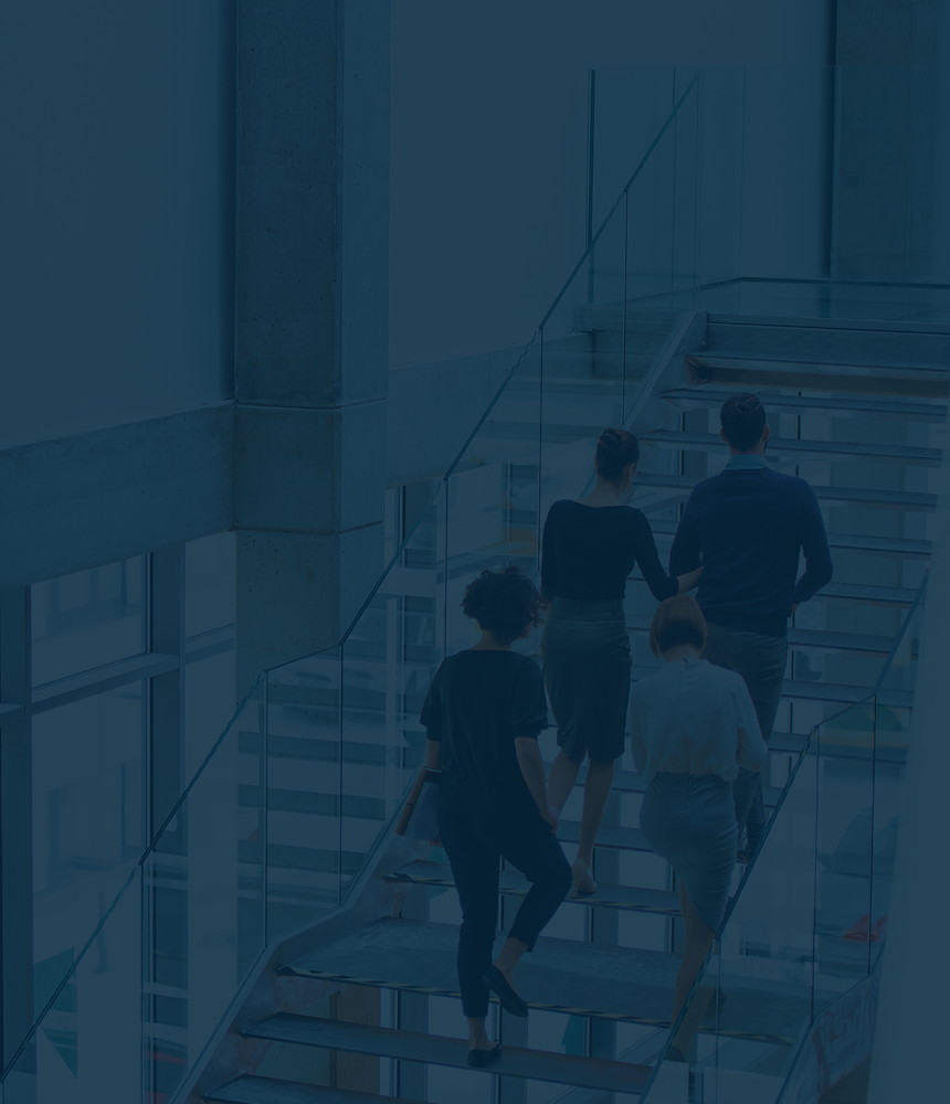 A team of professionals walking up stairs in a bright, modern office building.