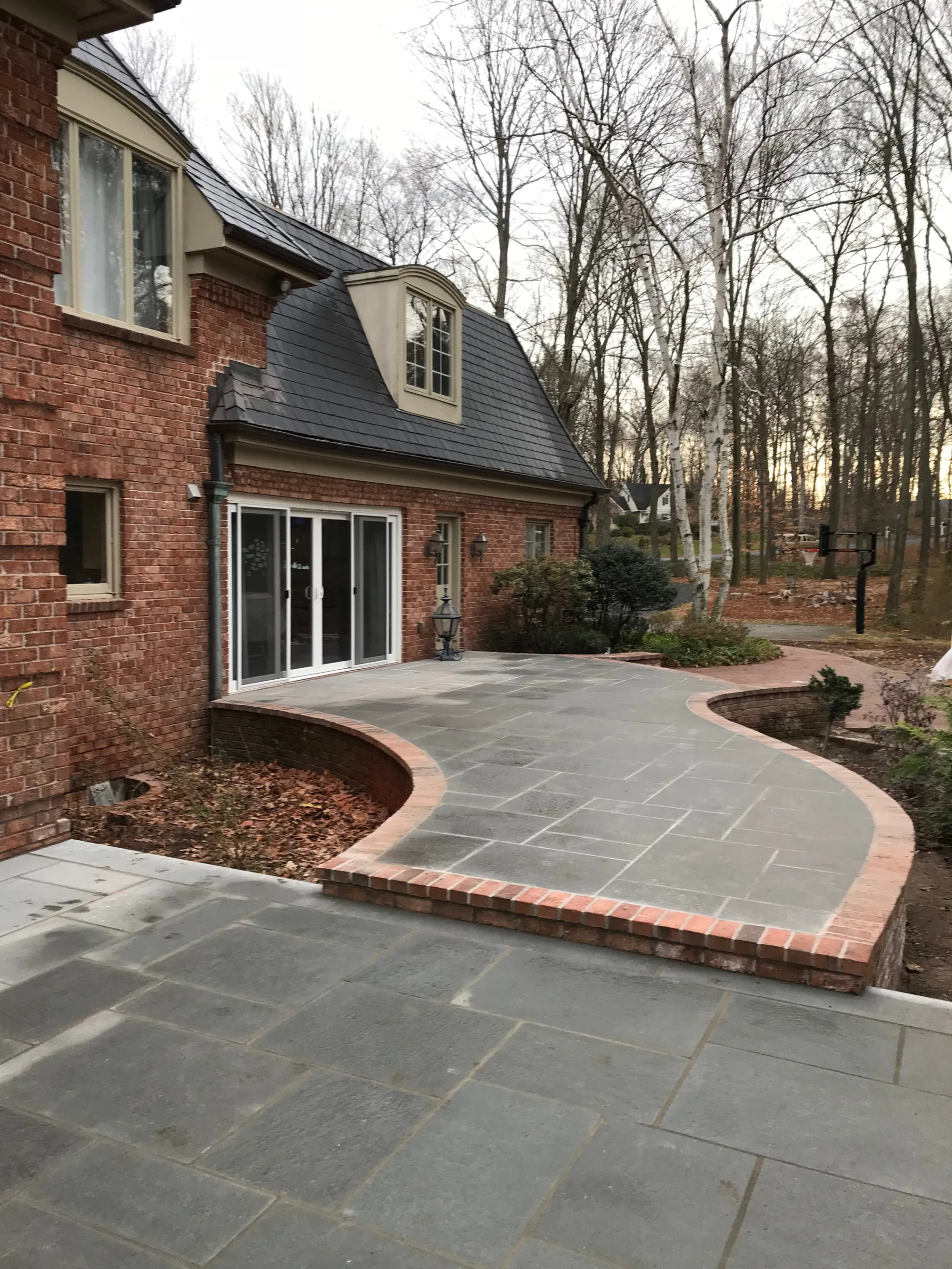 Stone patio in a landscaped backyard - Patios project by General Masonry LLC.