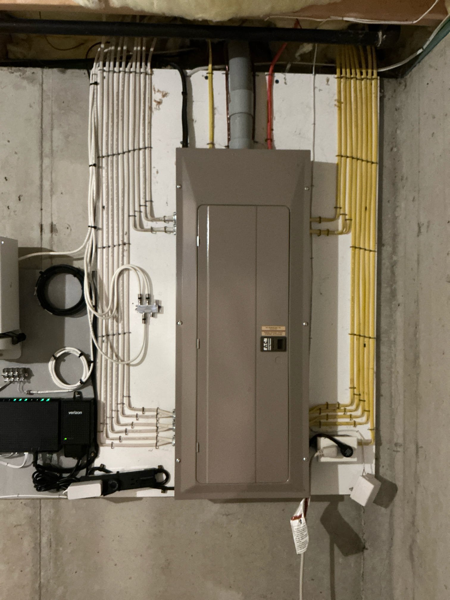An Eaton breaker panel installed by Thomas Edison Electric in a Lebanon, PA basement. The closed-door view shows the neatly organized Romex runs secured along the concrete foundation walls on both sides of the enclosure.
