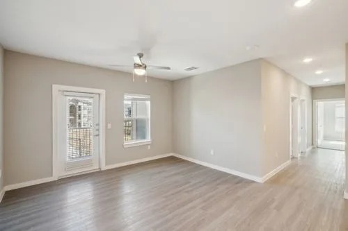 A spacious room with wood flooring and a ceiling fan.