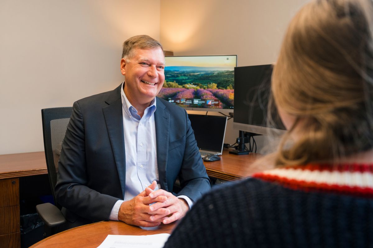 A financial advisor at Realize Financial Advisors smiling while speaking with a client during a pers 