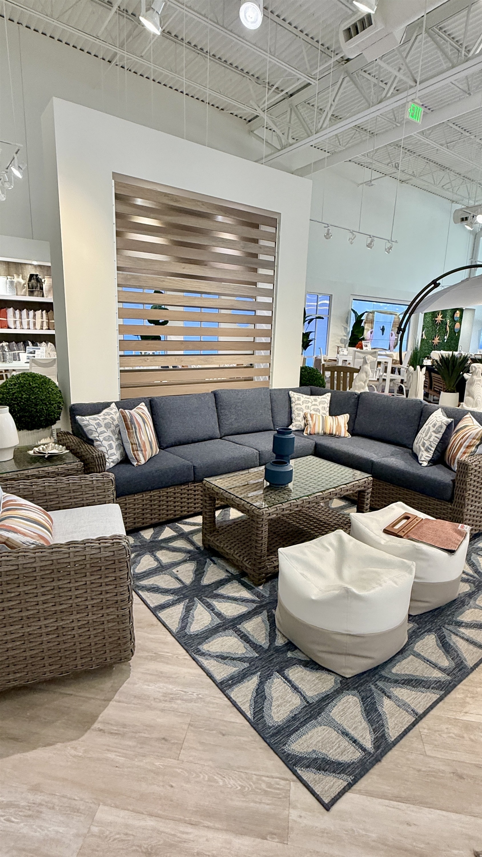 Relax in style with this wicker sectional sofa in charcoal cushions plus a glass-top coffee table at Rooms To Go Patio.