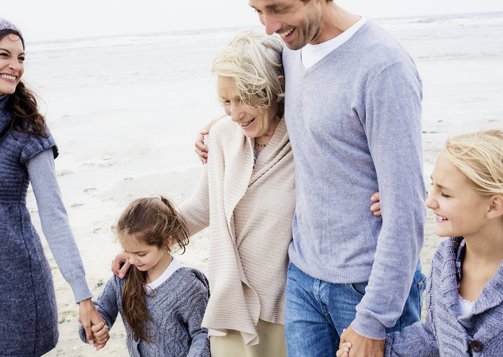 A multigenerational family walking along a beach.