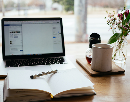 A laptop and coffee mug on a desk.
