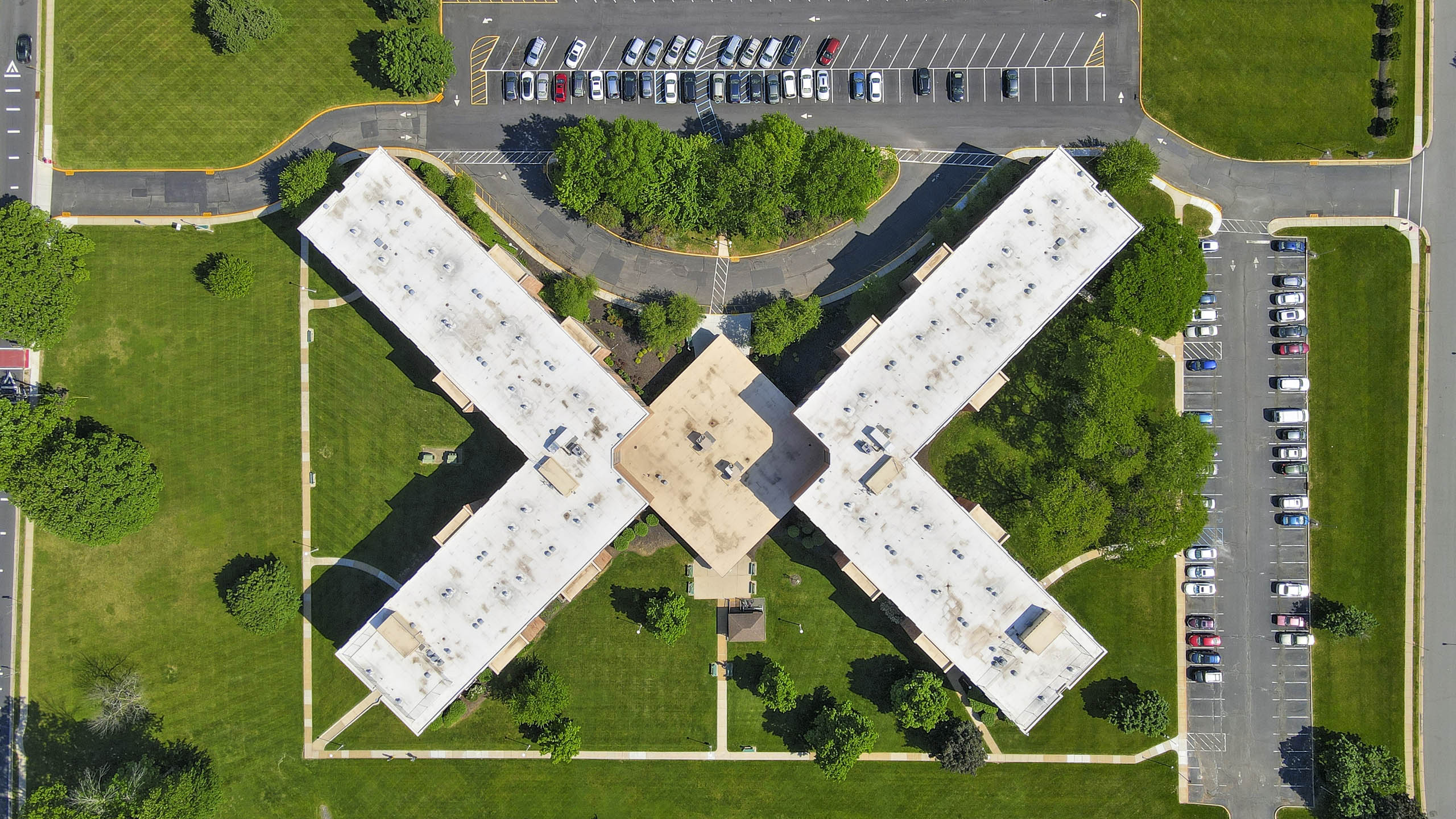 An aerial view of a parking lot with a large building in the center.