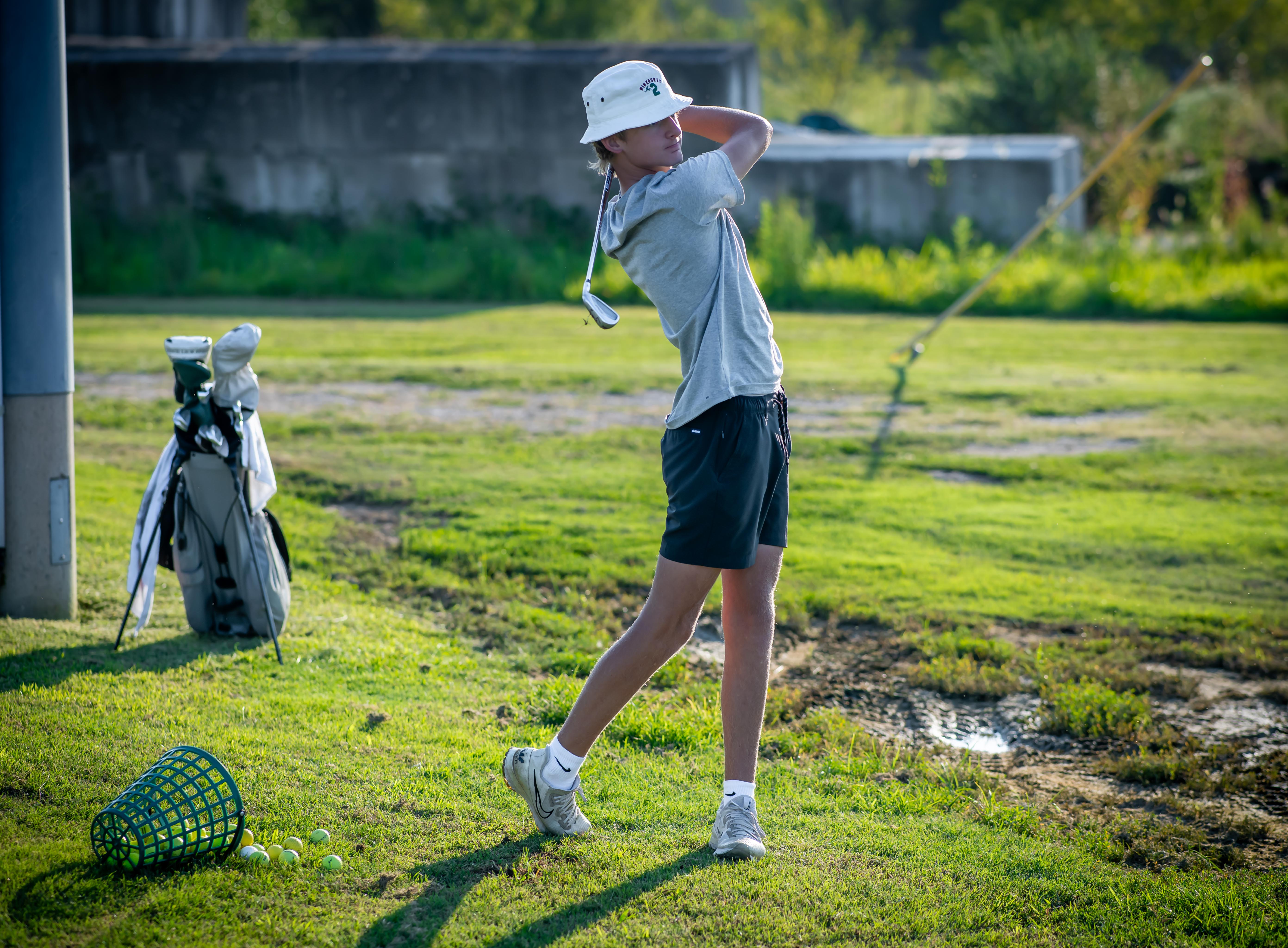 A golfer practices at the driving range at Tee Time Golf Complex in Evansville, IN, working on their swing in an outdoor setting.
