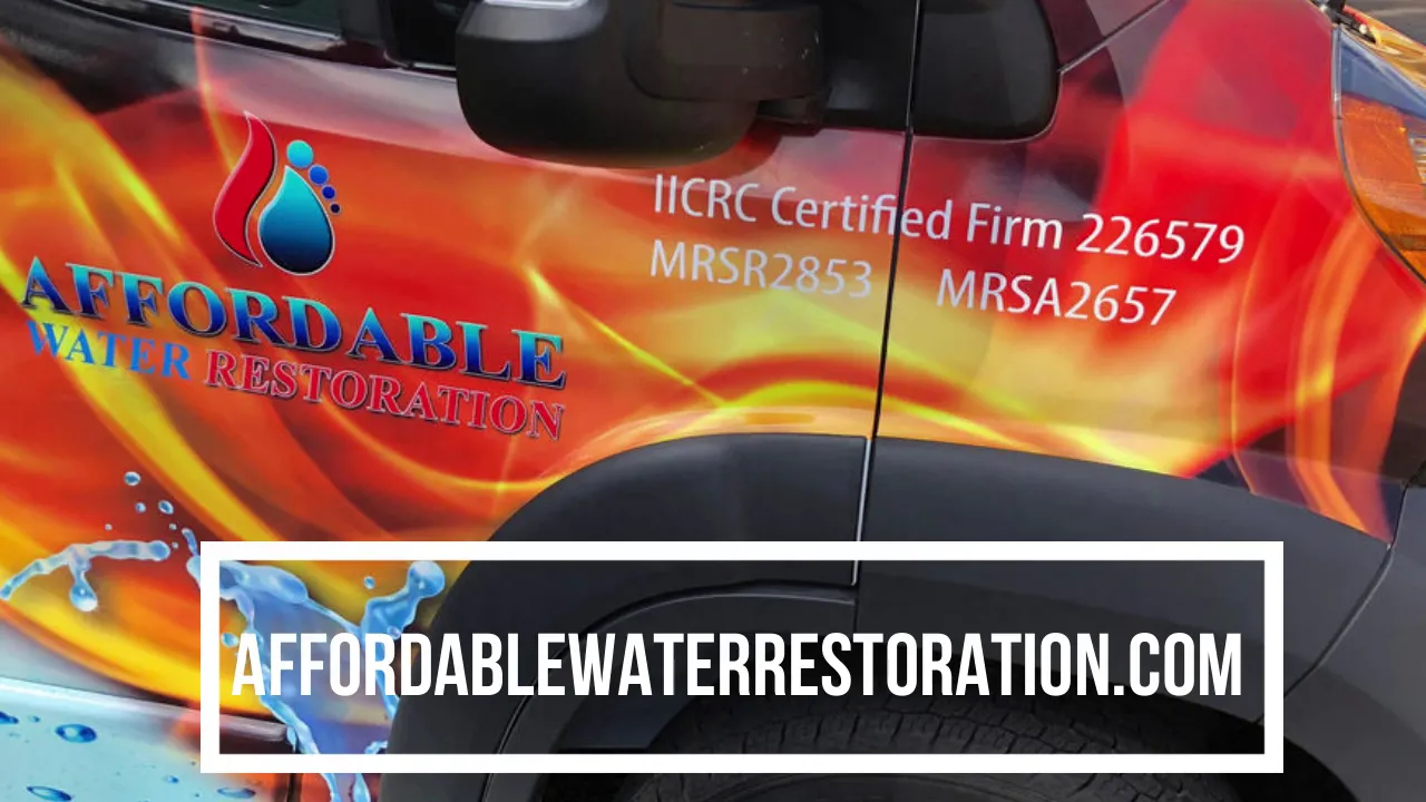A close-up shot of the side of a white van with a vibrant flame and water-themed graphic wrap. The wrap features the text "AFFORDABLE WATER RESTORATION" in blue and silver lettering with a logo above it. Below this, "IICRC Certified Firm 226579 MRS R2853 MRSA2657" is printed in white. A black rectangular box with white text "AFFORDABLEWATERRESTORATION.COM" is overlaid on the lower portion of the image. The van's dark gray wheel arch and part of the tire are visible.