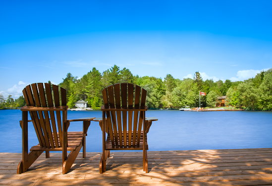 Two muskoka chairs by the water.