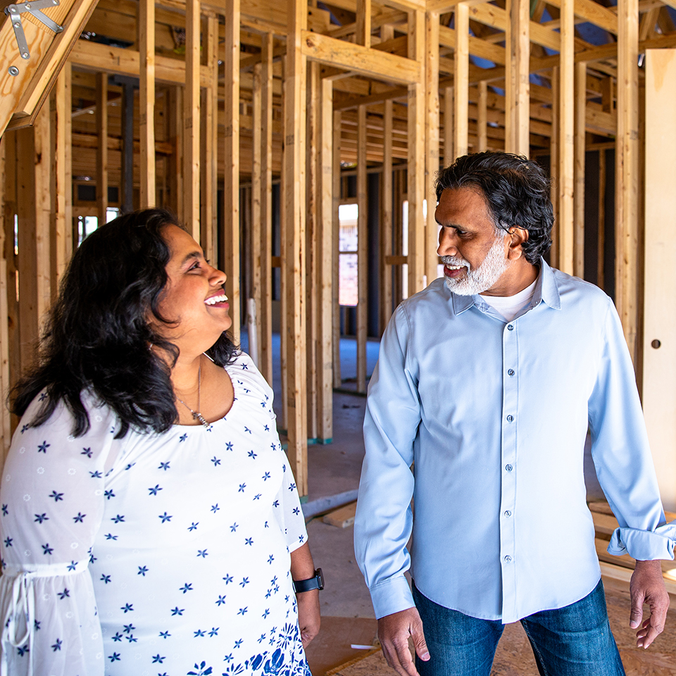 Two people walking through a house under construction