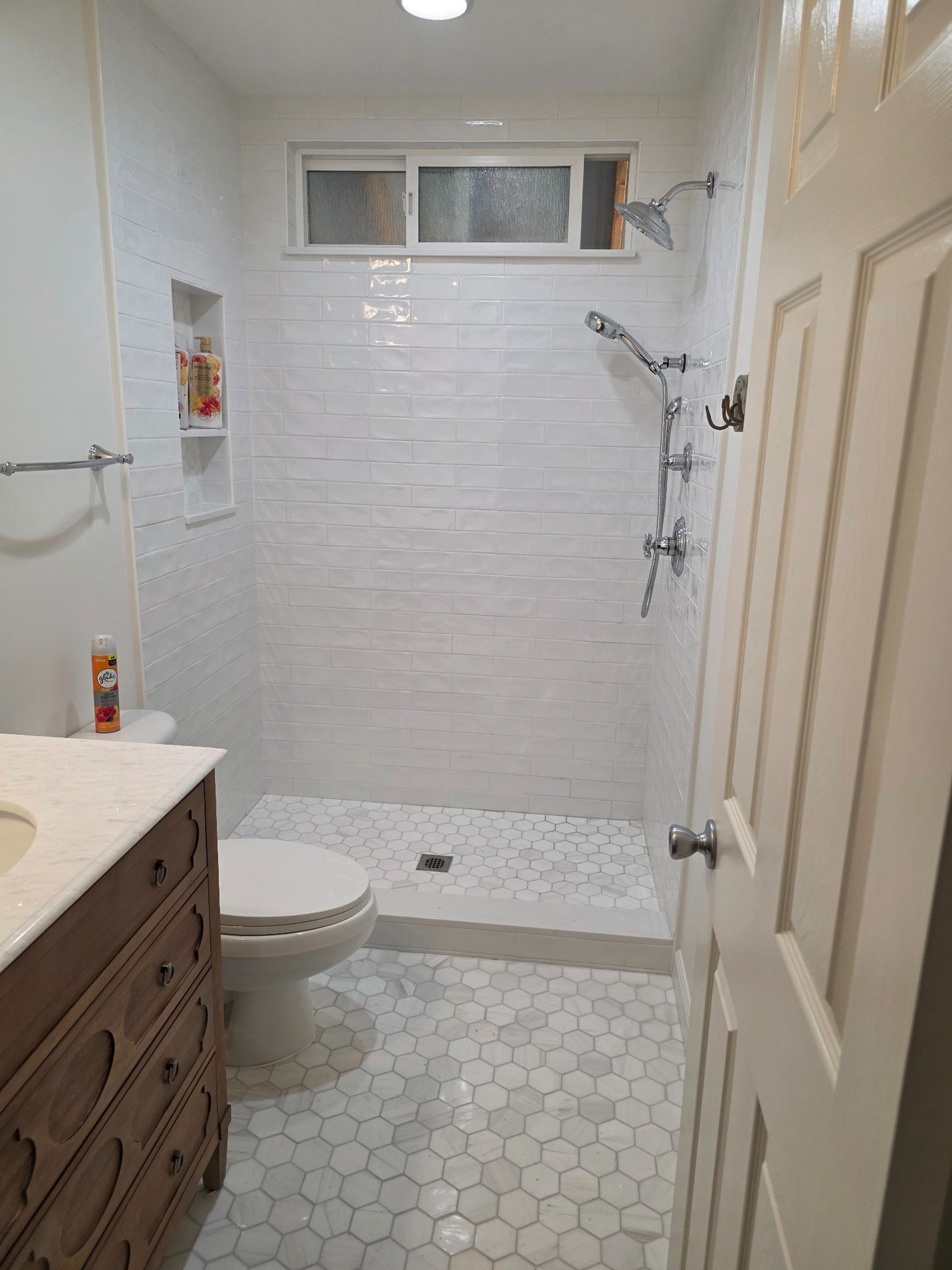 Compact bathroom renovation with tiled walk-in shower, new fixtures, vanity, and flooring. 