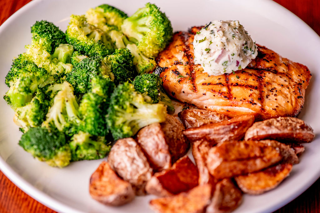 grilled salmon served with garlic roasted potatoes, broccoli, and topped with herb butter