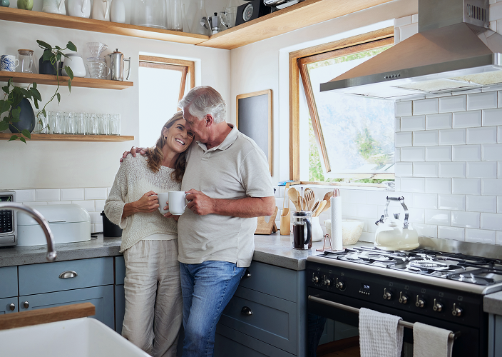 Clients hugging in their kitchen as they share a cup of coffee.