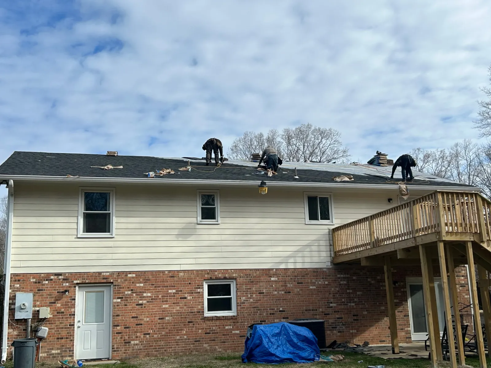 Roofing crew removing and replacing shingles on a two-story residence. 