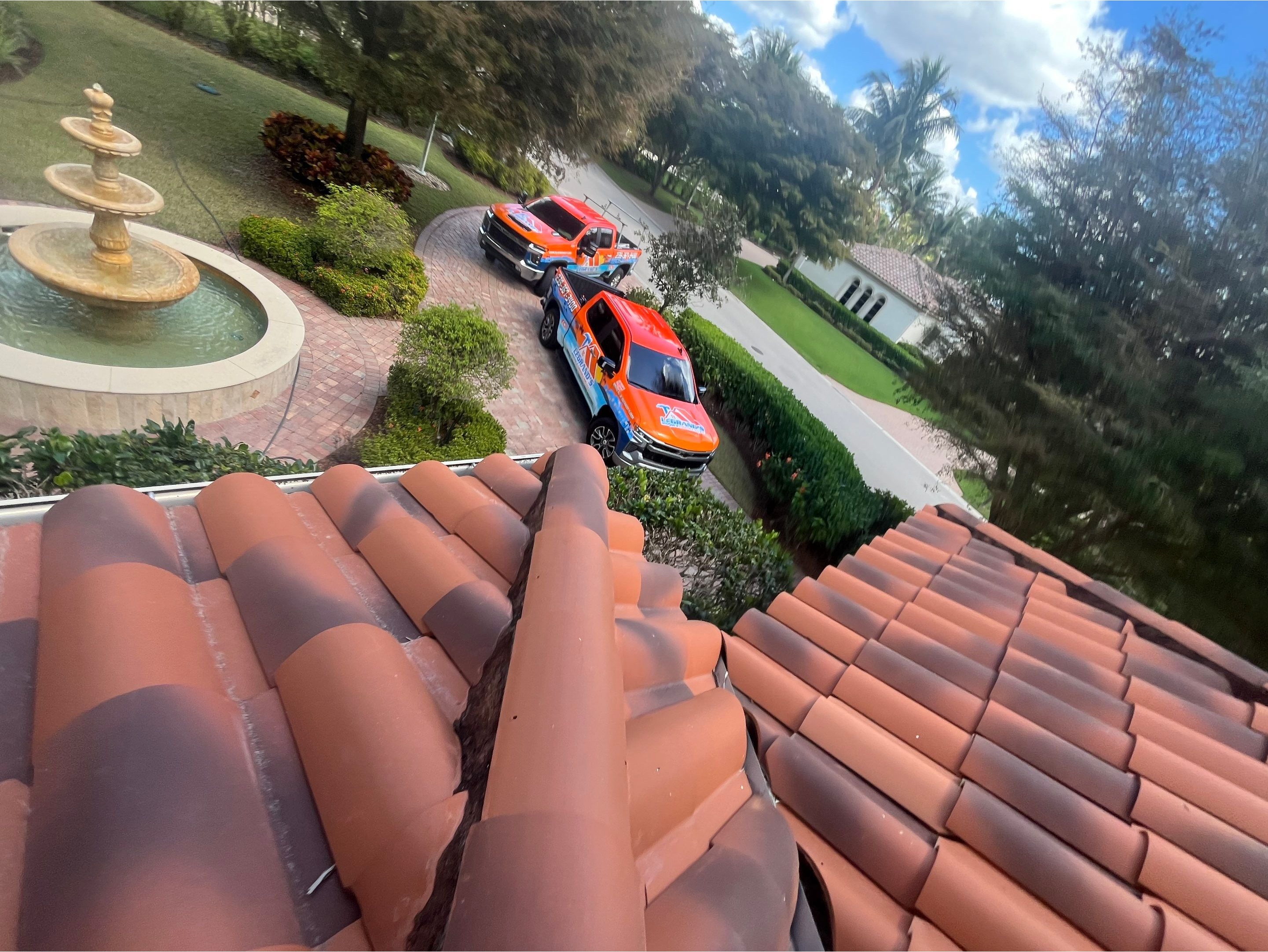View from a clay tile roof with a Legrand’s Roofing & Construction truck below, highlighting profess 