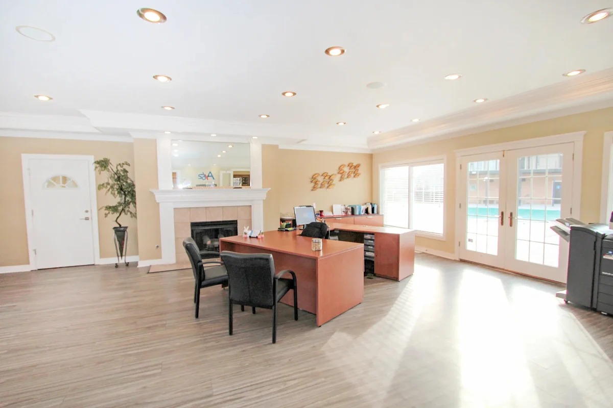 A spacious office with a desk, chairs, and a fireplace