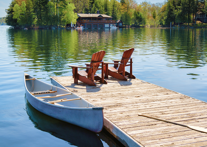 Muskoka chairs on the edge of a dock.